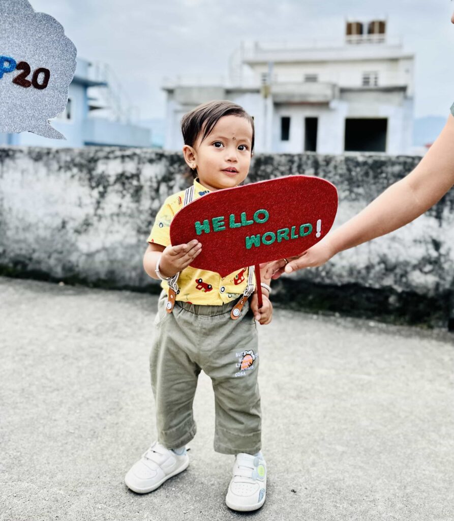 Baby holding a Hello World written prop in WP20 celebration